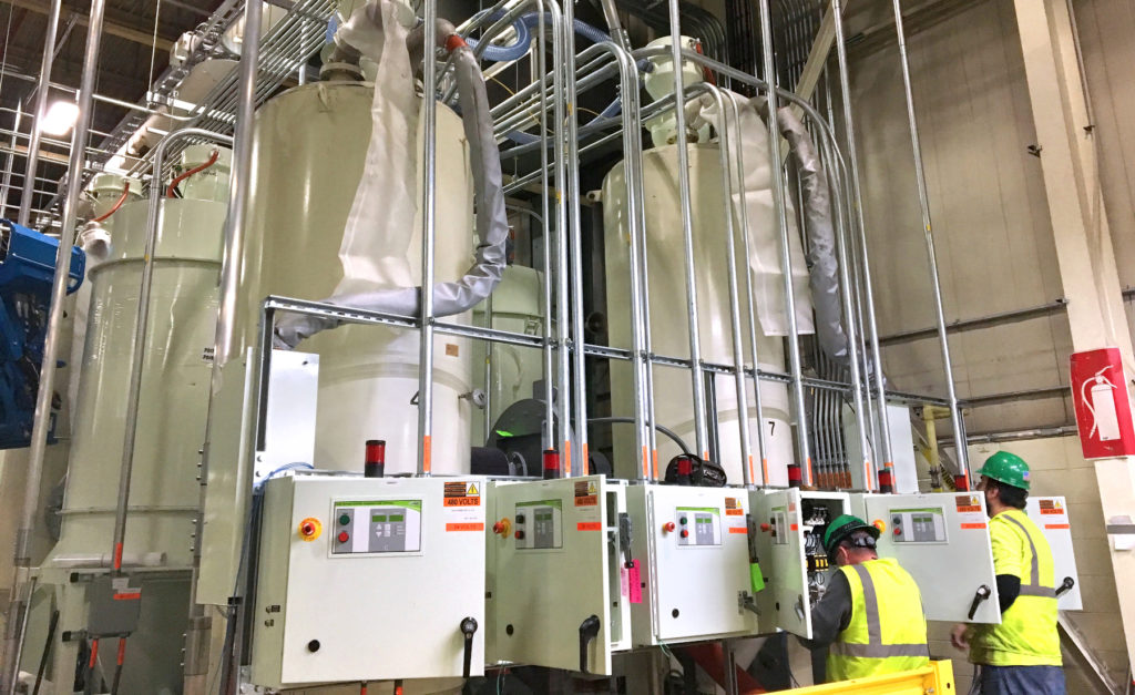 Black & McDonald tradespersons terminating electrical conductors in an equipment control panels