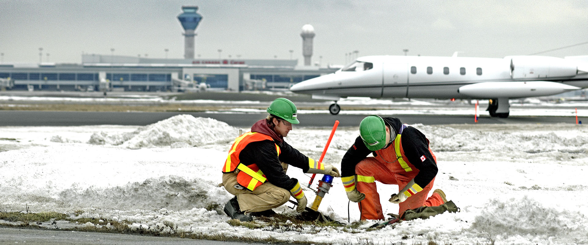 Two Black & McDonald technicians working on airport runway lighting.