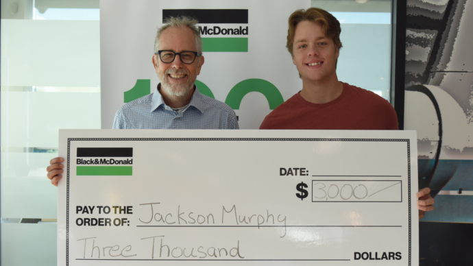 a Scholarship student receiving a novelty cheque from Ross McDonald