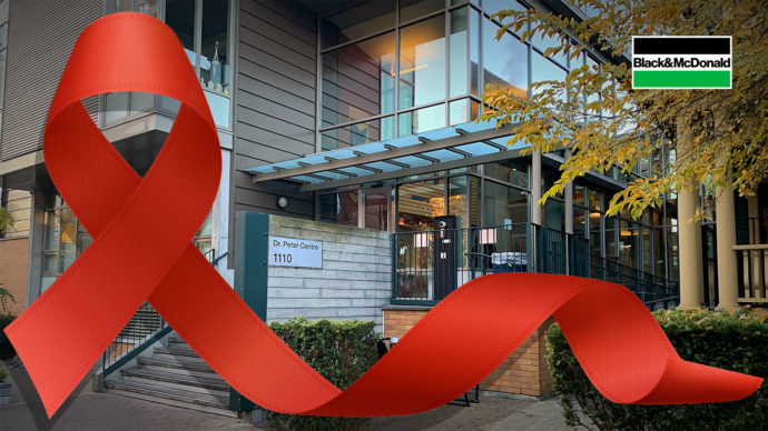 A large red ribbon in front of the Dr. Peter Centre building in Vancouver, BC.