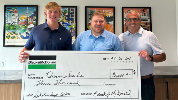 a Scholarship recipient receiving a novelty cheque from a Black & McDonald employee